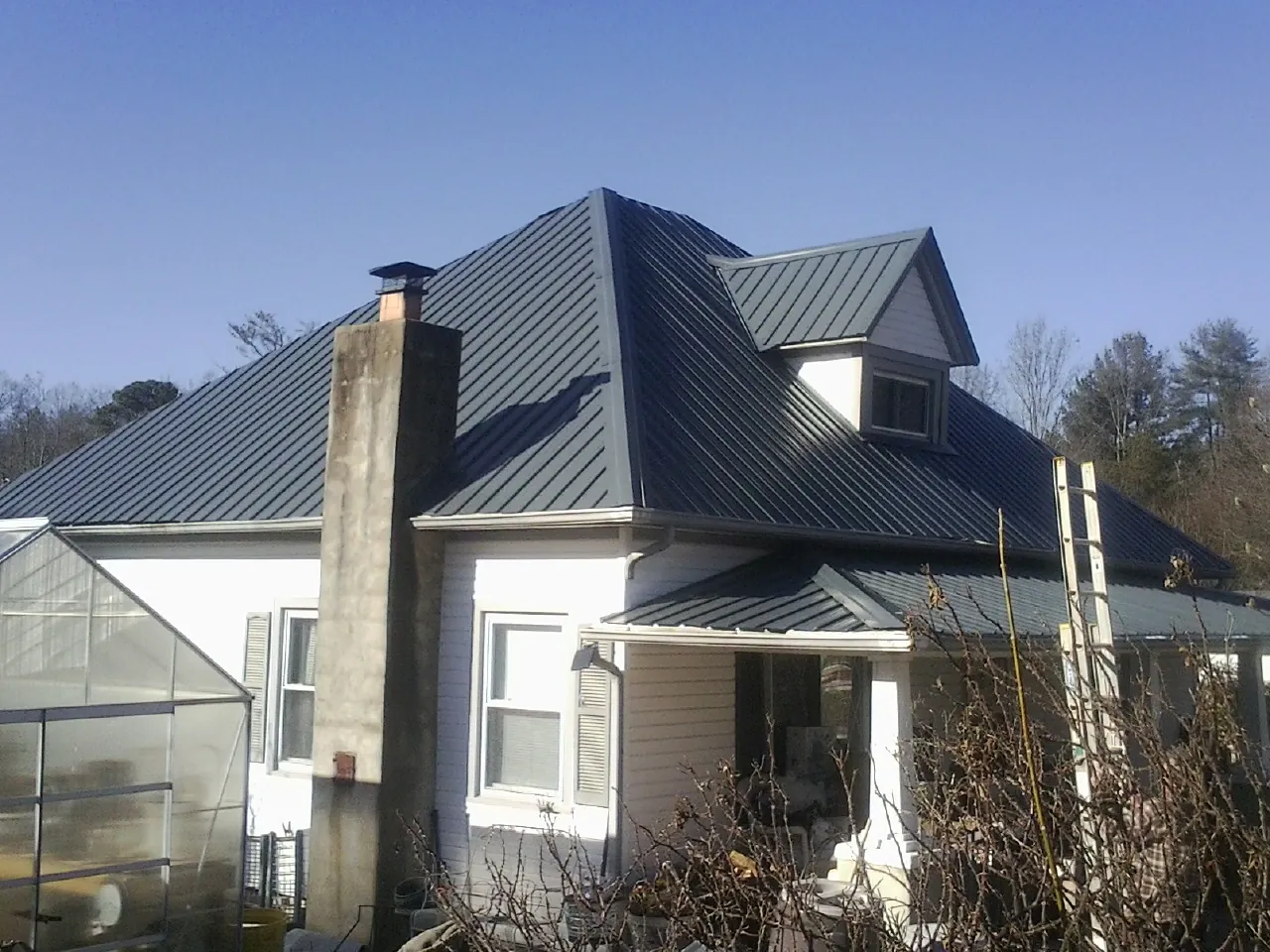 Dark blue standing seam metal roof on a white farmhouse with dormer — Slate & Tile Roof Repair by Roofing Brothers in Staunton