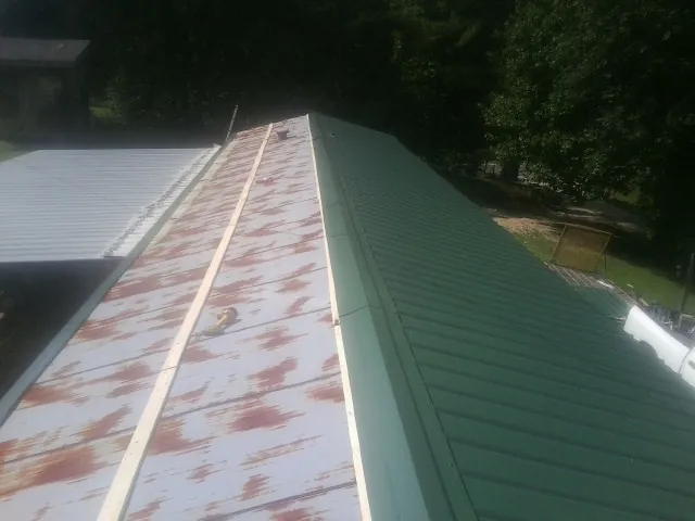 Old rusted panels beside newly installed green metal roofing — Wind Damage Roof Repair by Roofing Brothers in Staunton