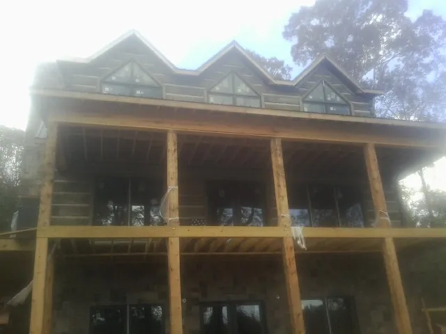 Dormers and porch framing on a large log home under construction — Roof Coating work by our crew in Staunton
