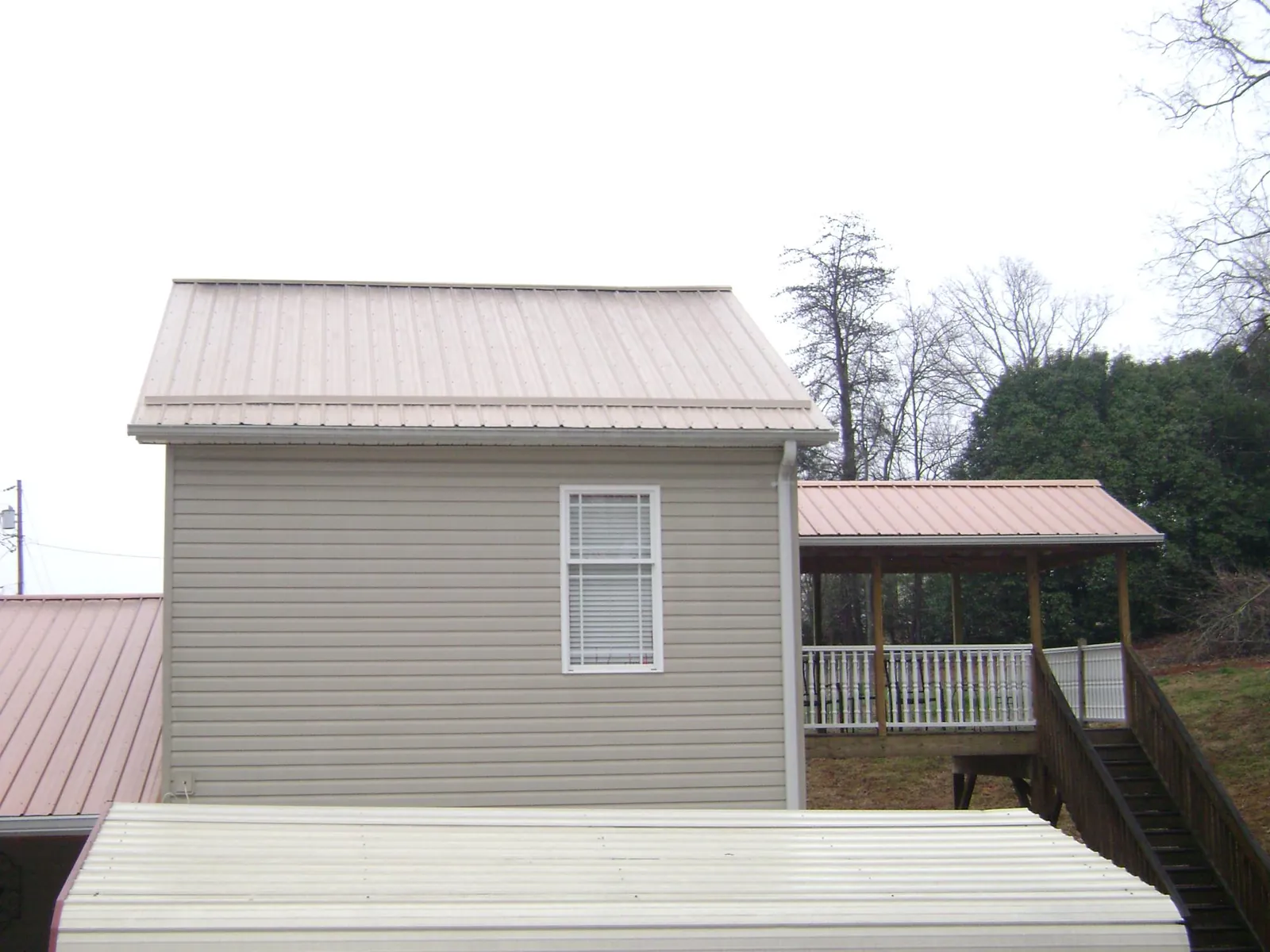 Tan metal roofs on a two story addition and attached porch, from a Roof Replacement job in Staunton
